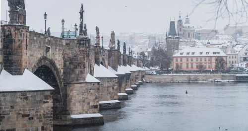 Prague in the snowfall. view of the charles bridge and the vltava river on a winter day. czechia