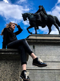 Statue of woman sitting by sculpture