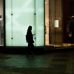 Side view of woman walking on footpath against building