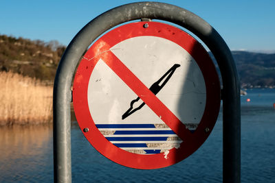 Close-up of arrow sign on road against sky