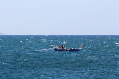 Men sailing on sea against clear sky