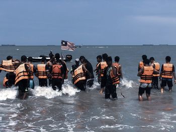 Rear view of people on sea against sky