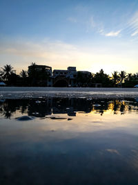 Scenic view of lake by buildings against sky at sunset