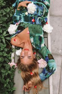 High angle portrait of woman with flowers lying outdoors