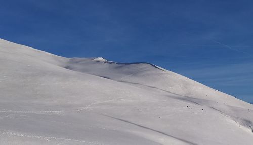 Low angle view of snowcapped mountain against blue sky