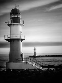 Lighthouse by sea against sky