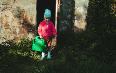 Girl came out of the barn with a watering can. the girl is engaged in agriculture. harvest care. 