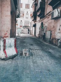 Wet street amidst buildings in city