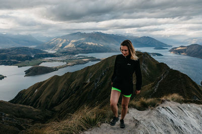 Full length portrait of young woman standing on lake against mountains