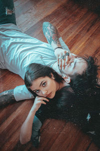 Portrait of young couple lying down on wooden floor