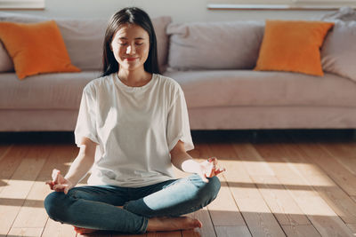 Young woman sitting on sofa at home