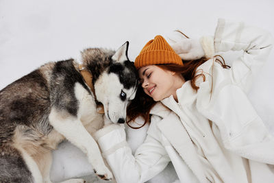 High angle view of young woman with dog on snow covered land