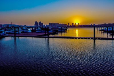 View of river and illuminated buildings at sunset