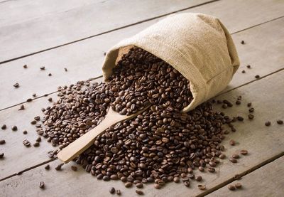 Roasted coffee beans spilling from sack on table