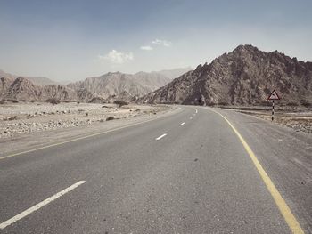 Road by mountains against sky