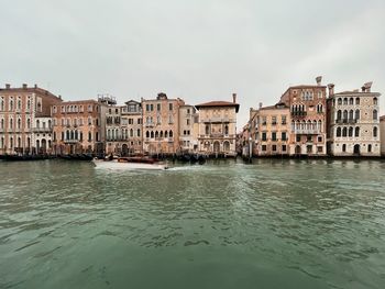 Buildings by river against sky