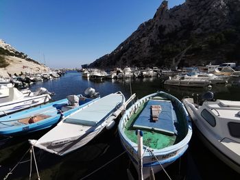 Sailboats moored at harbor against clear blue sky