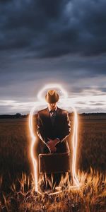 Man sitting on field during sunset