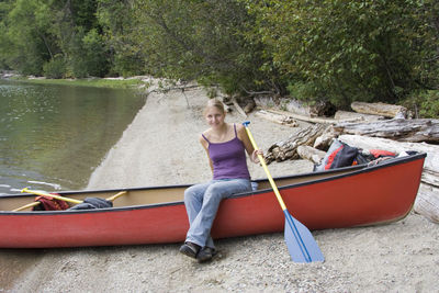 Young woman sitting on boat at lake