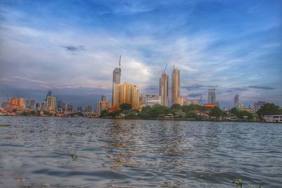 River by city buildings against sky