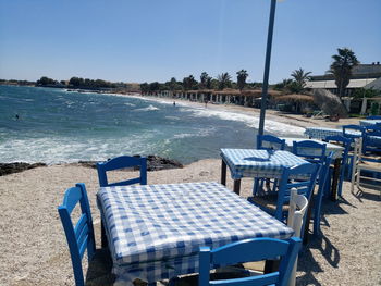 Chairs and table by swimming pool against clear sky