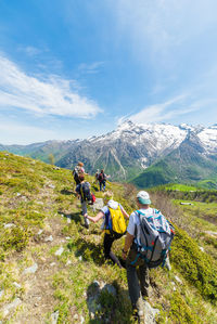 Rear view of people walking on mountain against sky