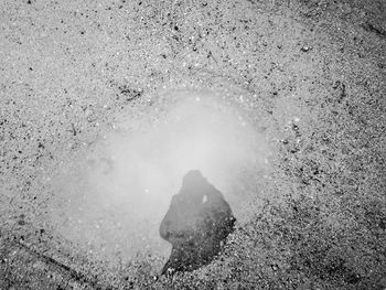 Puddle with reflection of person on sandy beach