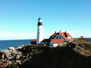 Lighthouse on shore against blue sky