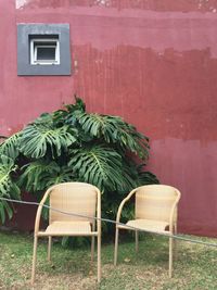 Empty chairs and table against building wall