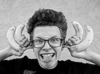 Black and white portrait of teenage boy holding bananas and making a funny face