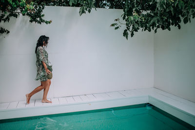 Woman standing by swimming pool against trees