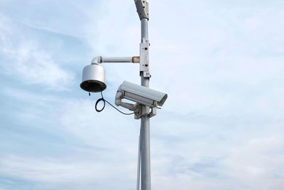 Low angle view of security camera on pole against sky