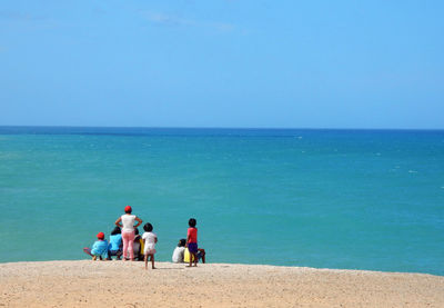 People on beach against clear sky