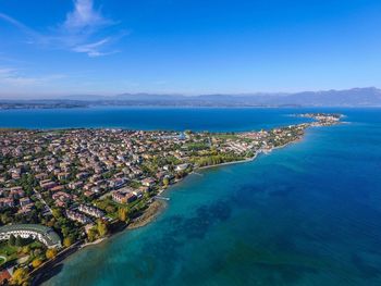 Aerial view of town by sea against blue sky