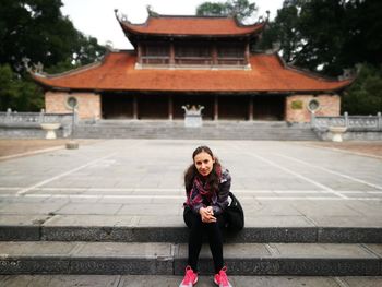 Portrait of smiling woman sitting on steps against building