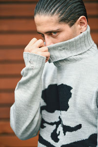 Portrait of young man standing against wall