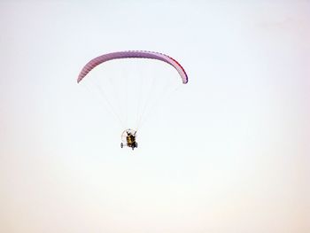 Low angle view of person motor paragliding against clear sky