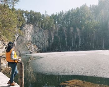 Rear view of woman standing by river against sky