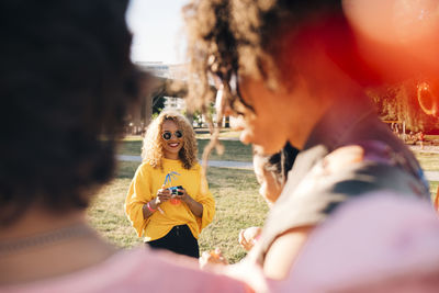 Smiling woman with friends enjoying at concert on sunny day