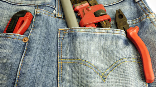 Close-up of hand tools in jeans pockets