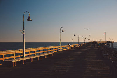 Pier over sea against sky during sunset