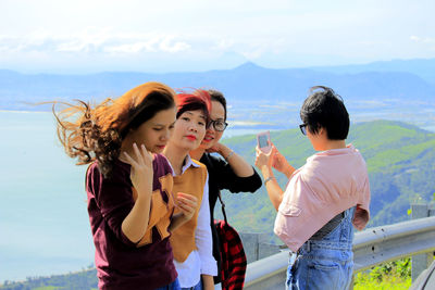 Young women standing against sky