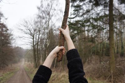 Man holding tree trunk in forest