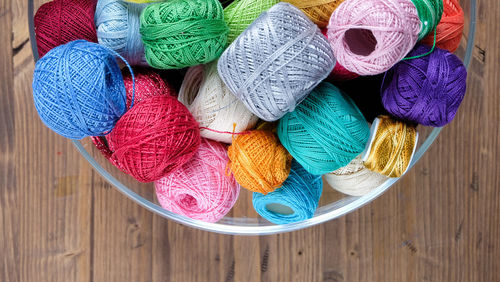 Directly above view of colorful thread balls in container on table