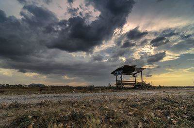 Silhouette windmill on field against sky at sunset