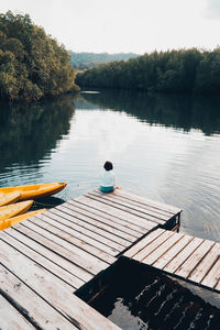 High angle view of girl sitting on pier over lake