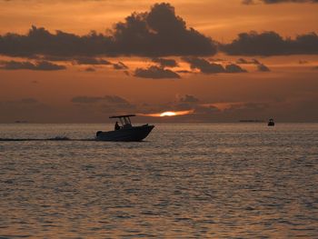 Silhouette boat in sea against sky during sunset