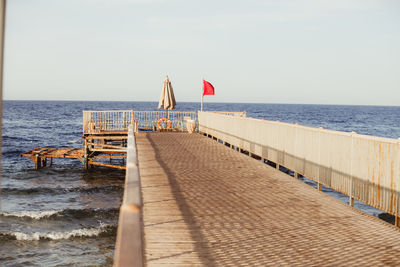 Pier on beach against clear sky