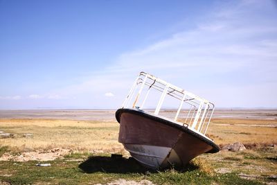 Abandoned ship on field against sky