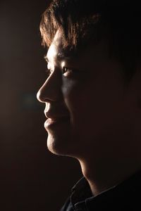 Close-up of man with eyes closed against black background